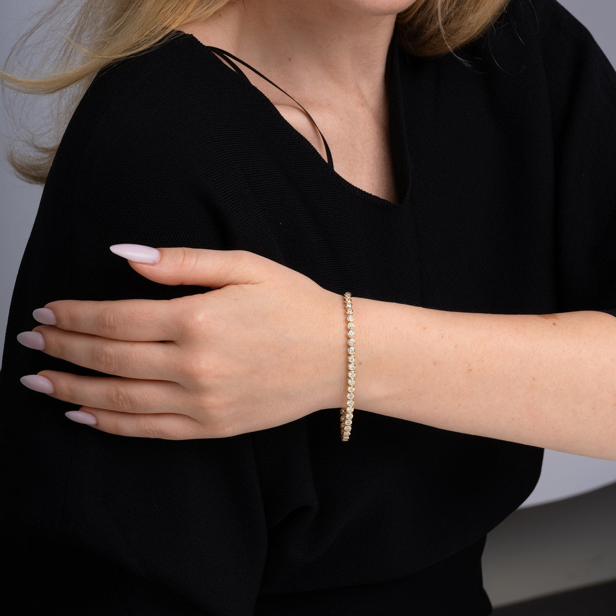 Bezel set diamond tennis bracelet worn on the wrist in 14K yellow gold #Metal_Yellow Gold