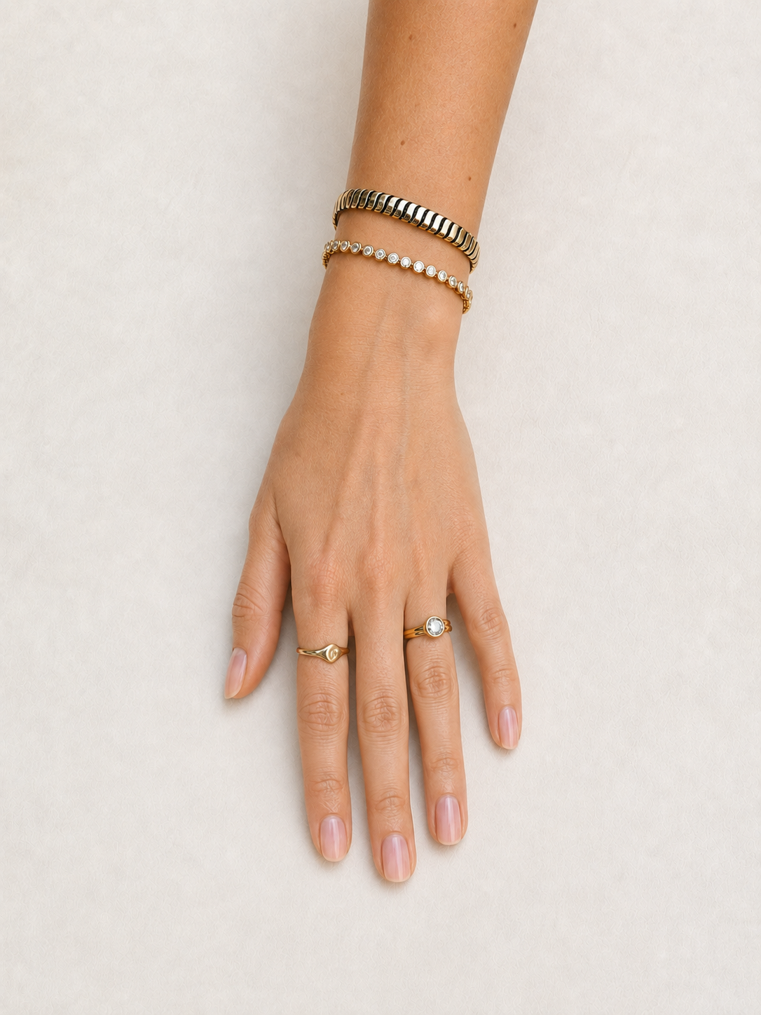 Bezel set diamond tennis bracelet in 14K yellow gold, worn on the hand and styled with a gold cuff #Metal_Yellow Gold