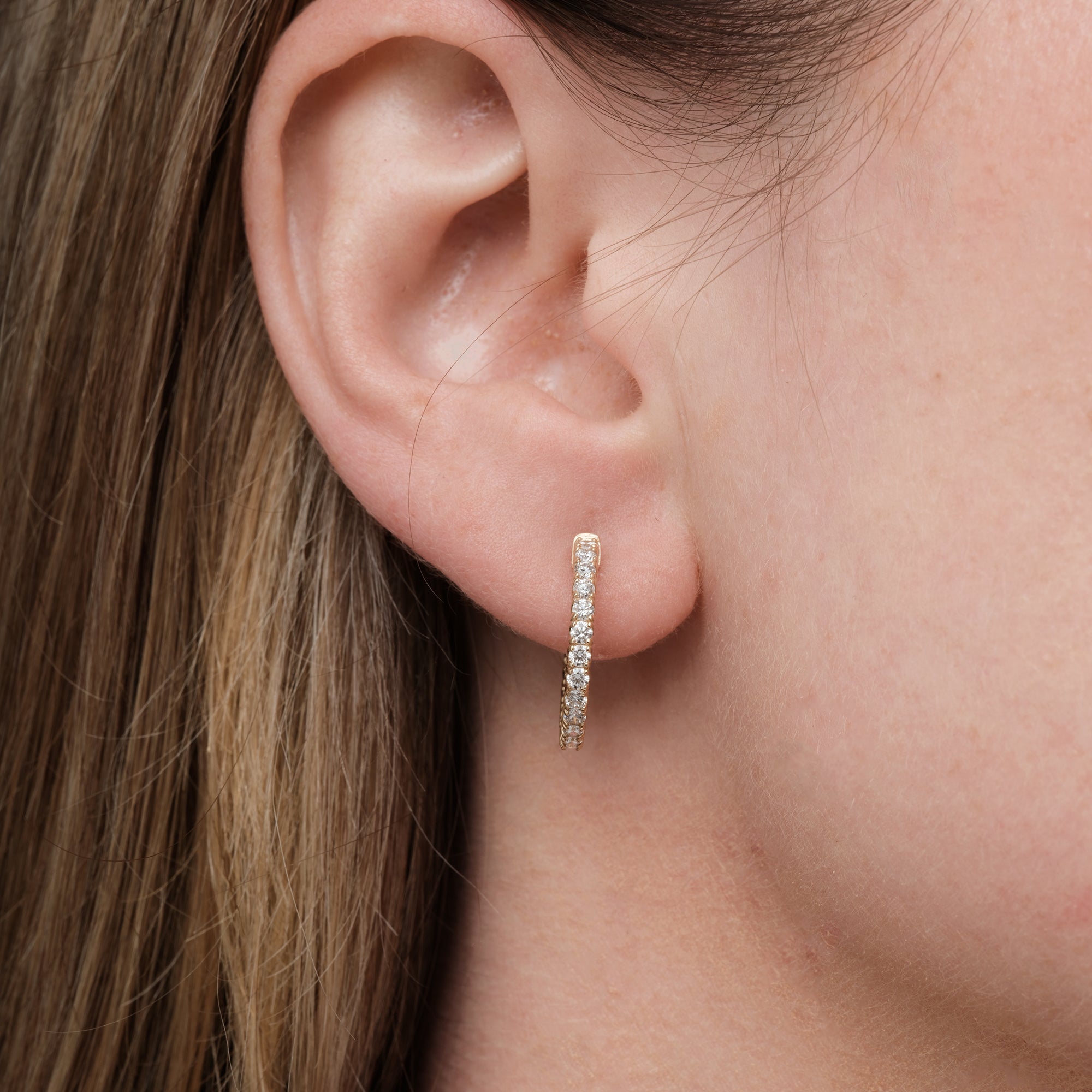 Model wearing diamond hoop earrings, side profile of the ear