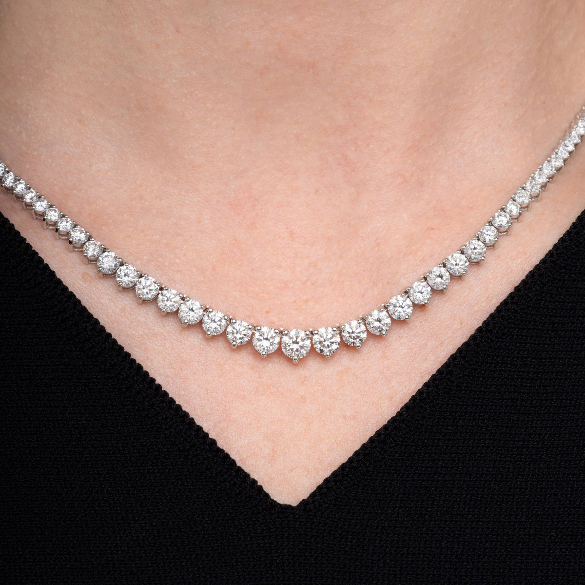 Graduated round diamond tennis necklace worn at the collarbone
