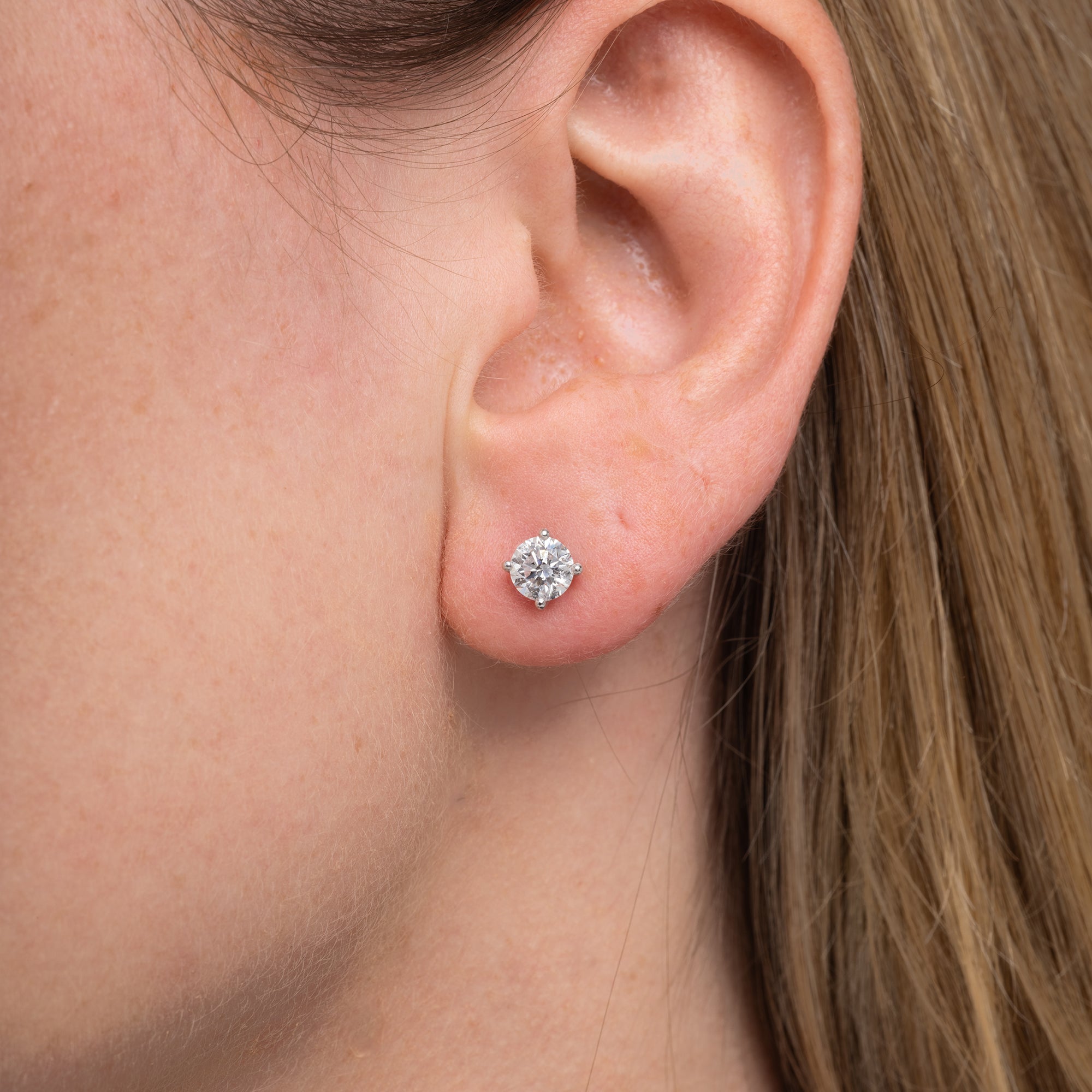 Round lab grown diamond stud earrings worn on the ear, 1.07 carat total weight