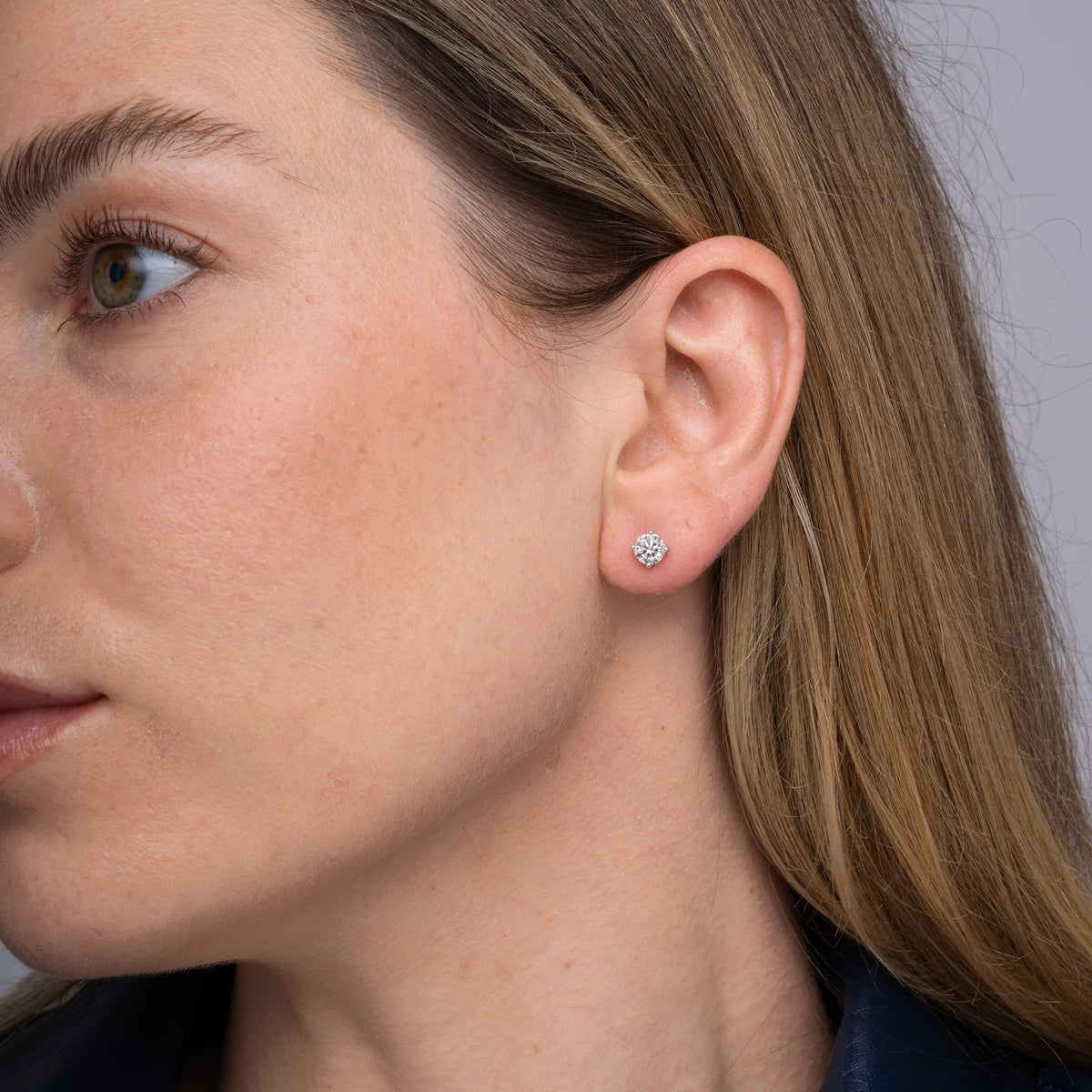 Round lab grown diamond stud earrings worn on the ear, 1.07 carat total weight