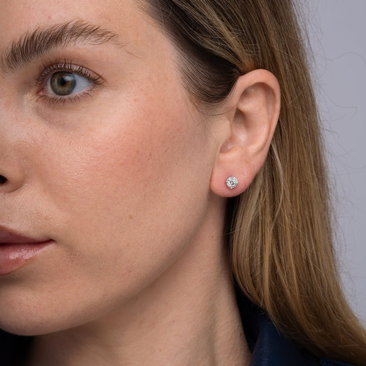 Round lab grown diamond stud earrings worn on the ear, 1.07 carat total weight