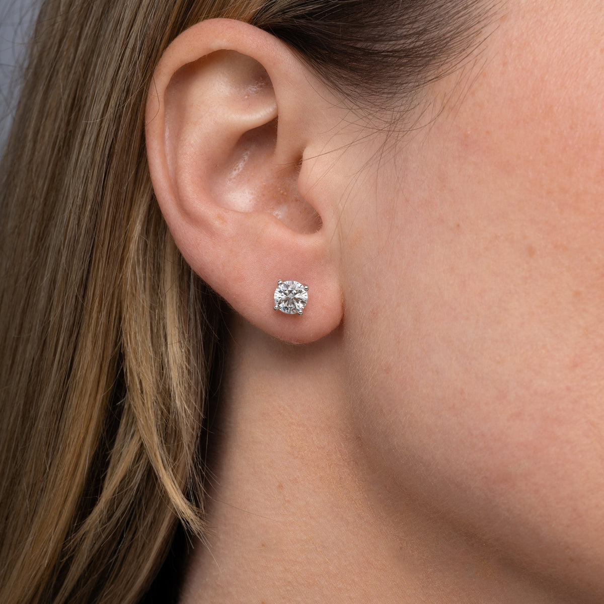 Round lab grown diamond stud earring worn on the ear, side profile
