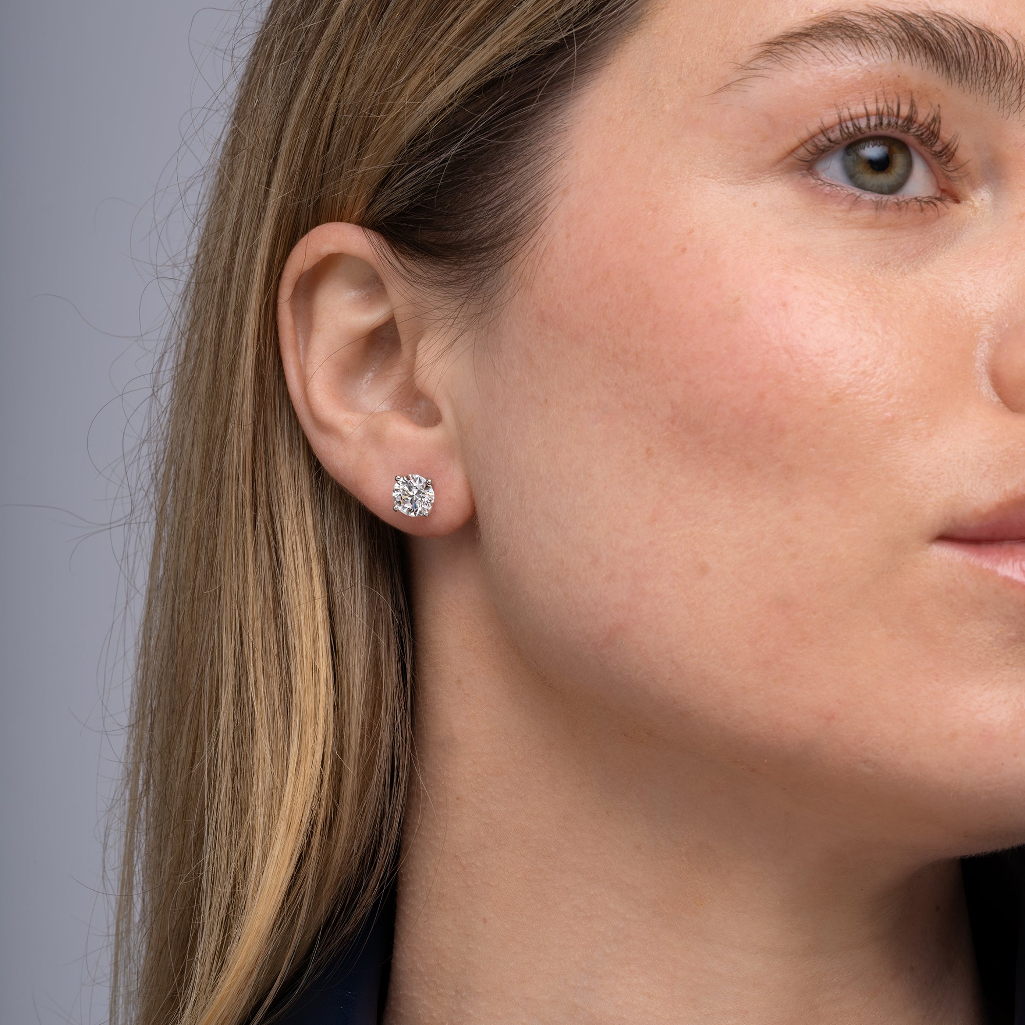 Round lab grown diamond stud earrings worn on the ear, 3.18 carat total weight
