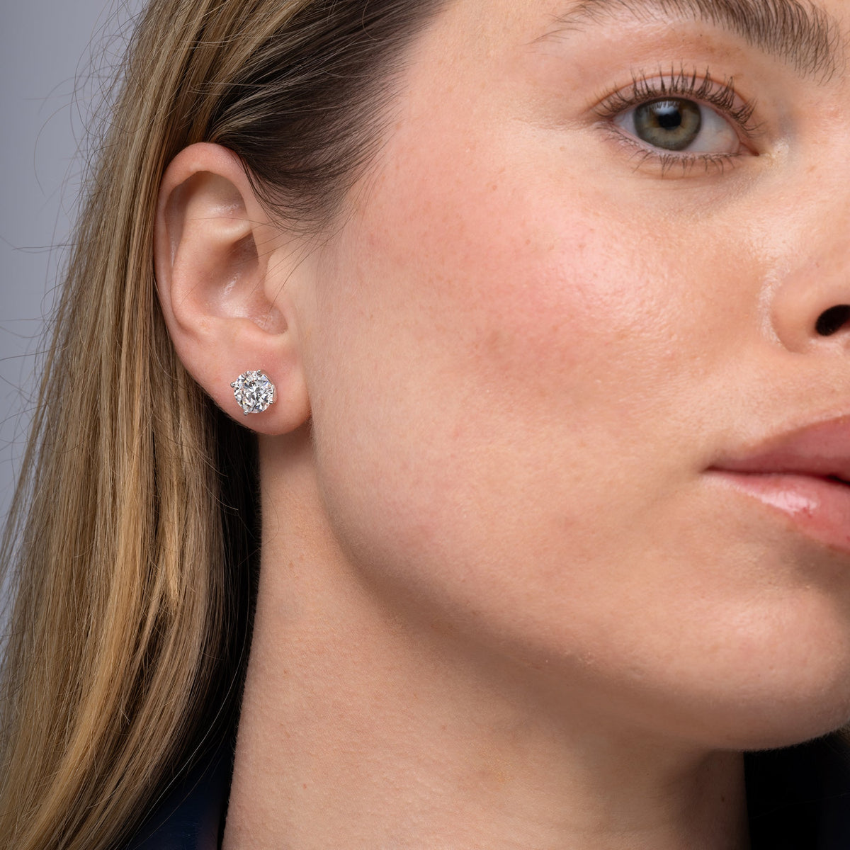Round lab grown diamond stud earrings worn on the ear, 4.14 carat total weight