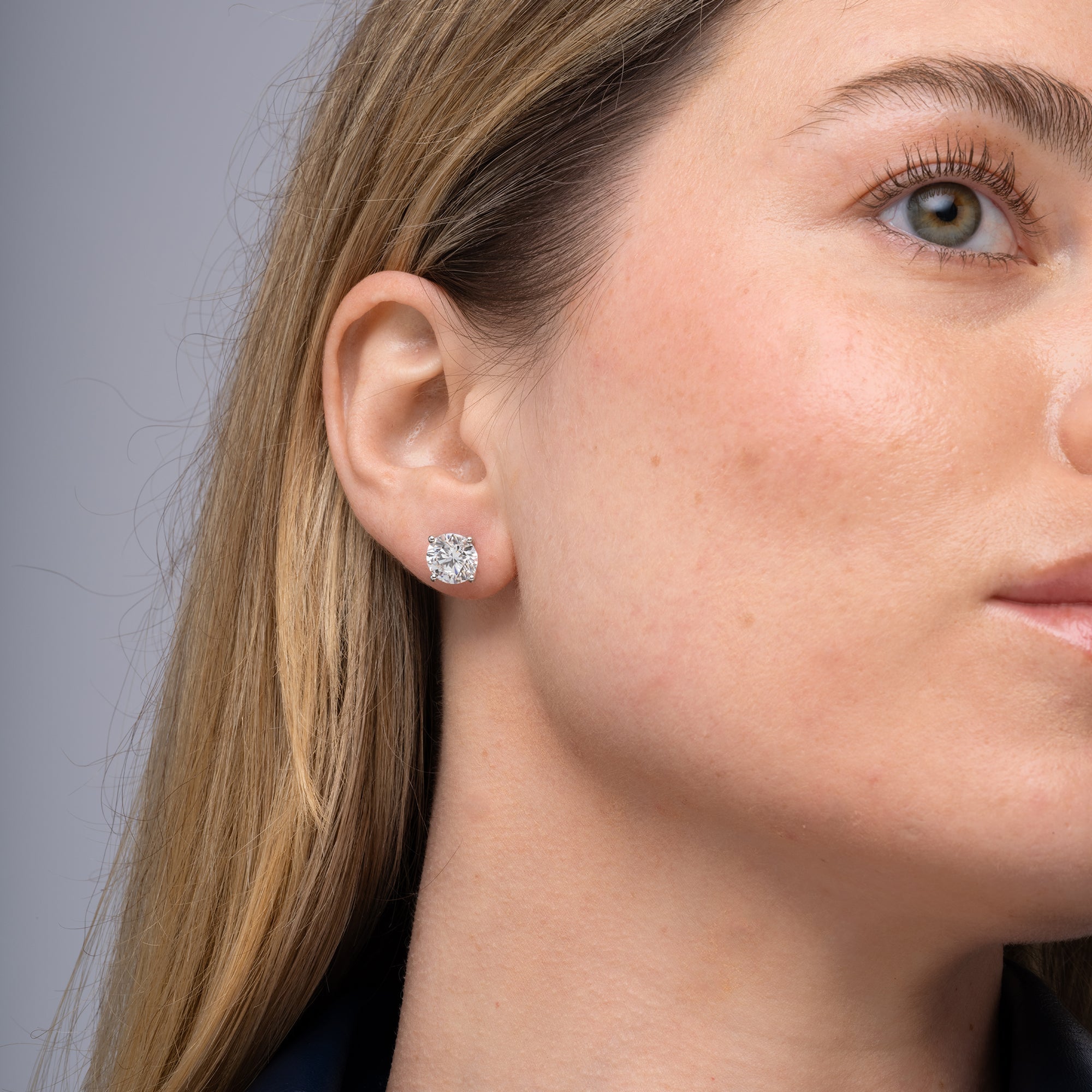 Round lab grown diamond stud earrings worn on the ear, 5.09 carat total weight