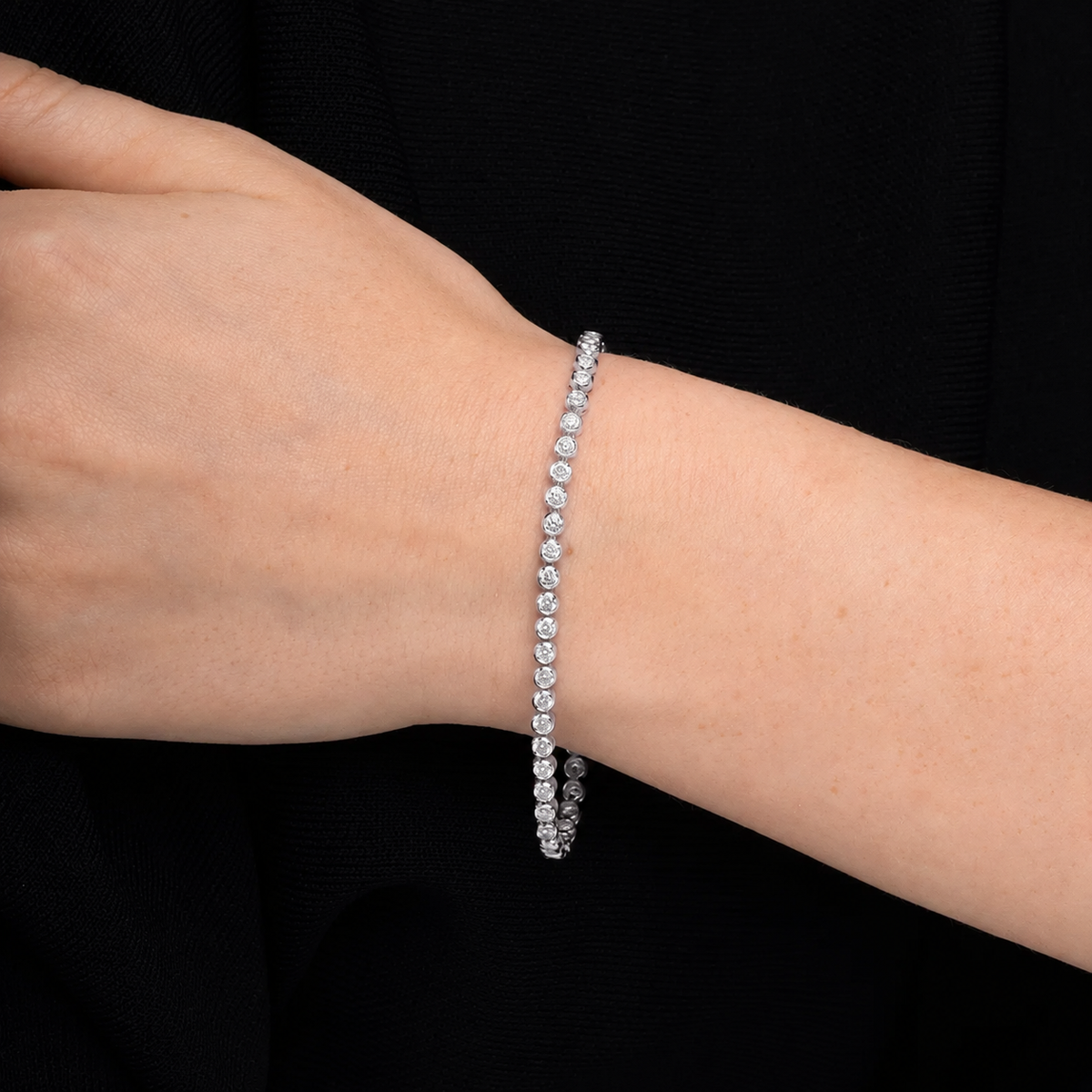 Bezel set diamond tennis bracelet in 14K white gold, worn on the wrist #Metal_White Gold