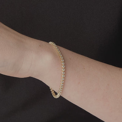 Bezel set diamond tennis bracelet shown in motion on the wrist #Metal_Yellow Gold