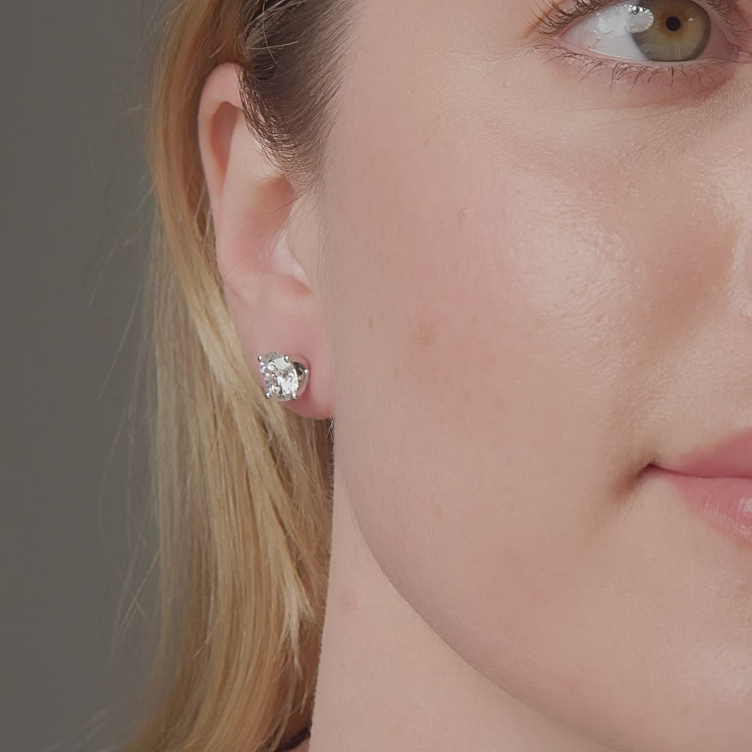Round diamond stud earrings shown in motion on the ear, 4.14 carat total weight