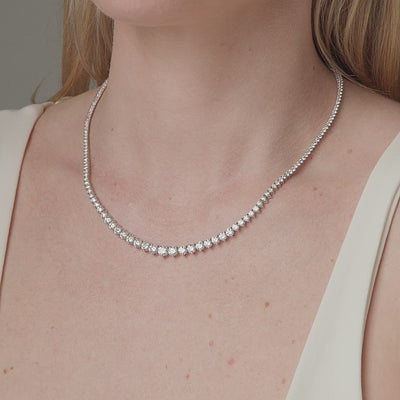 Graduated round diamond tennis necklace shown in motion on the neck