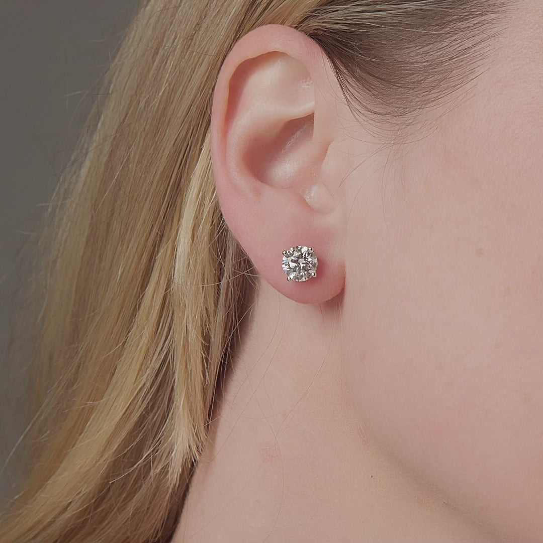 Round diamond stud earrings shown in motion on the ear, 3.18 carat total weight