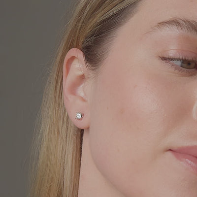 Round diamond stud earrings shown in motion on the ear, 1.07 carat total weight