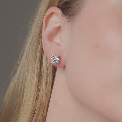 Round diamond stud earrings shown in motion on the ear, 5.09 carat total weight