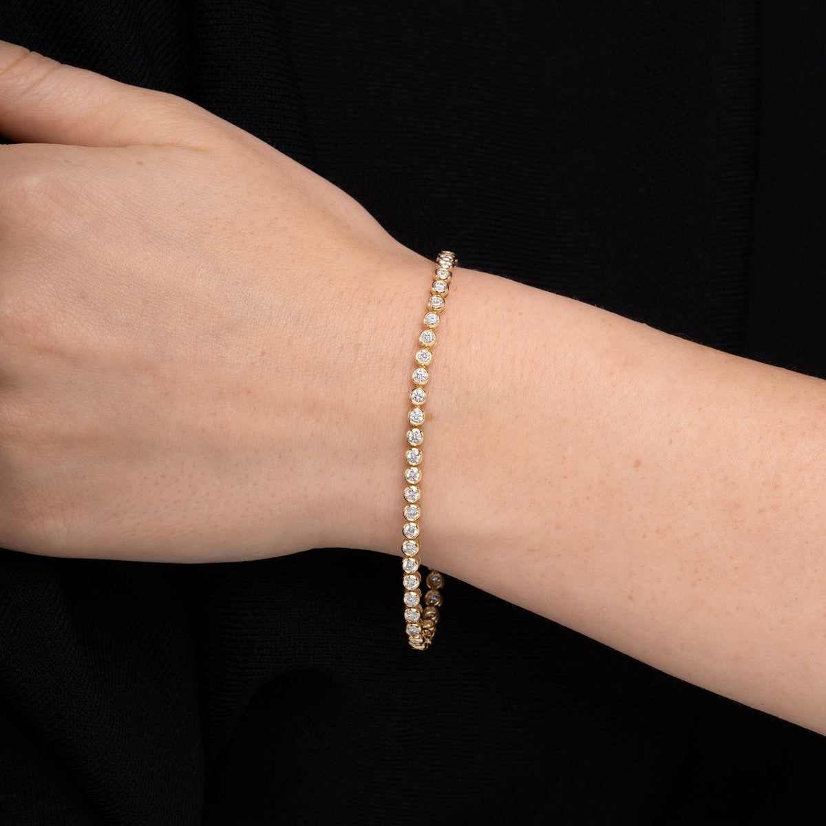 Bezel set diamond tennis bracelet worn on the wrist in 14K yellow gold #Metal_Yellow Gold