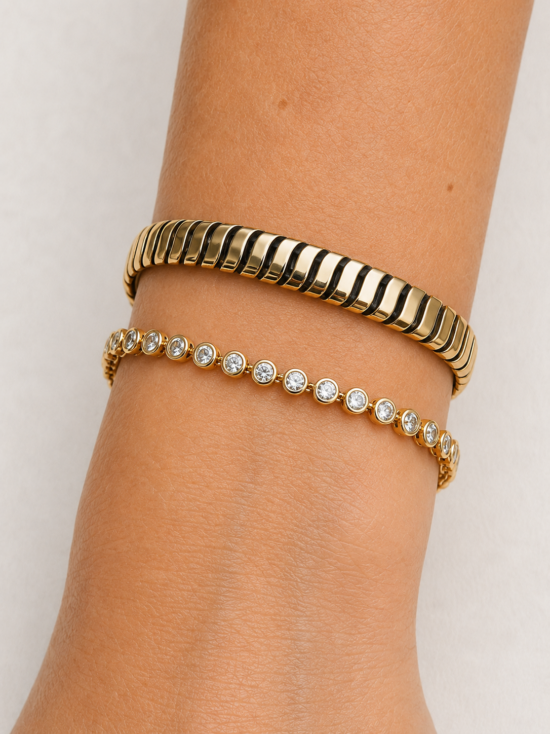 Bezel set diamond tennis bracelet in 14K yellow gold, close up on the wrist beside a gold cuff #Metal_Yellow Gold