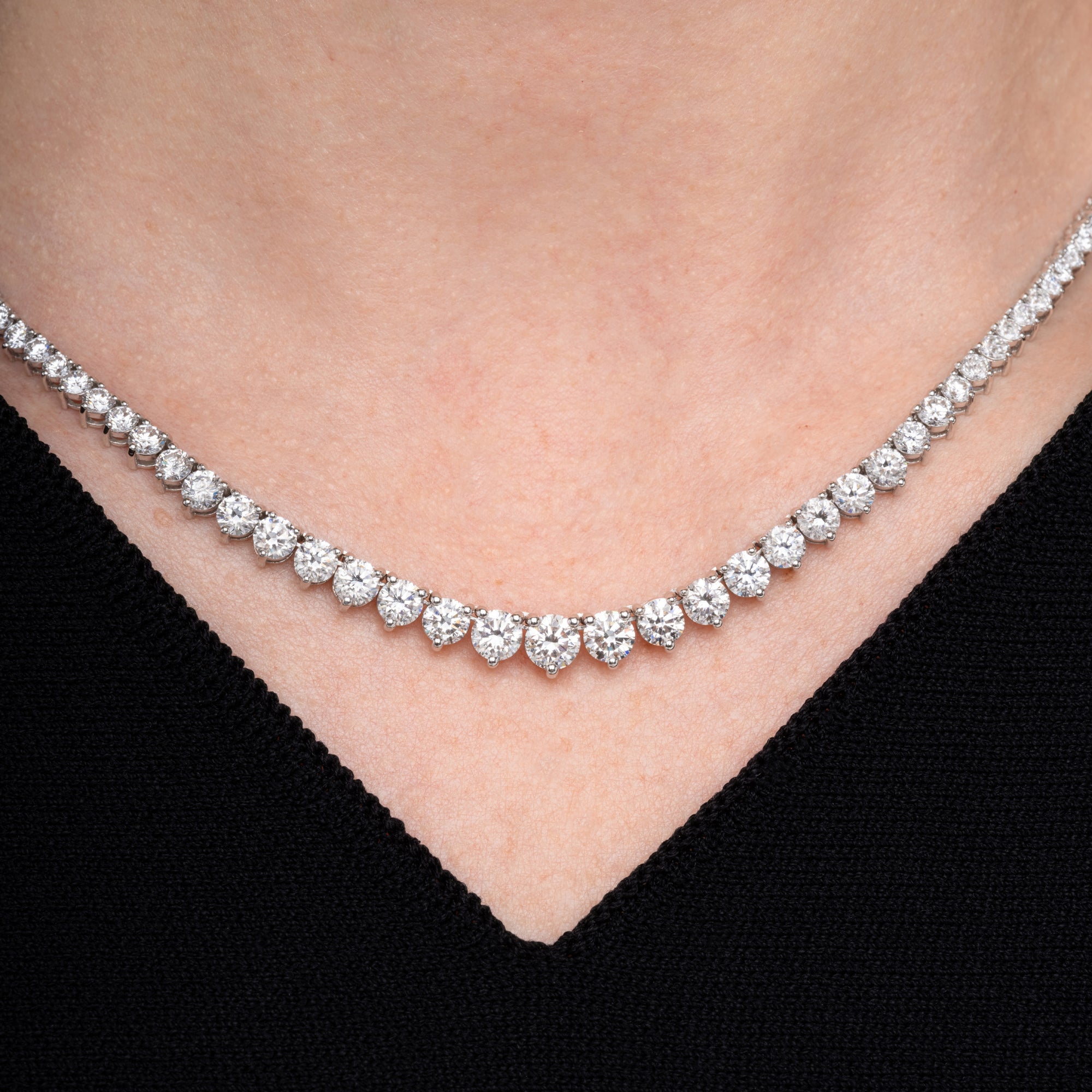 Graduated round diamond tennis necklace worn at the collarbone