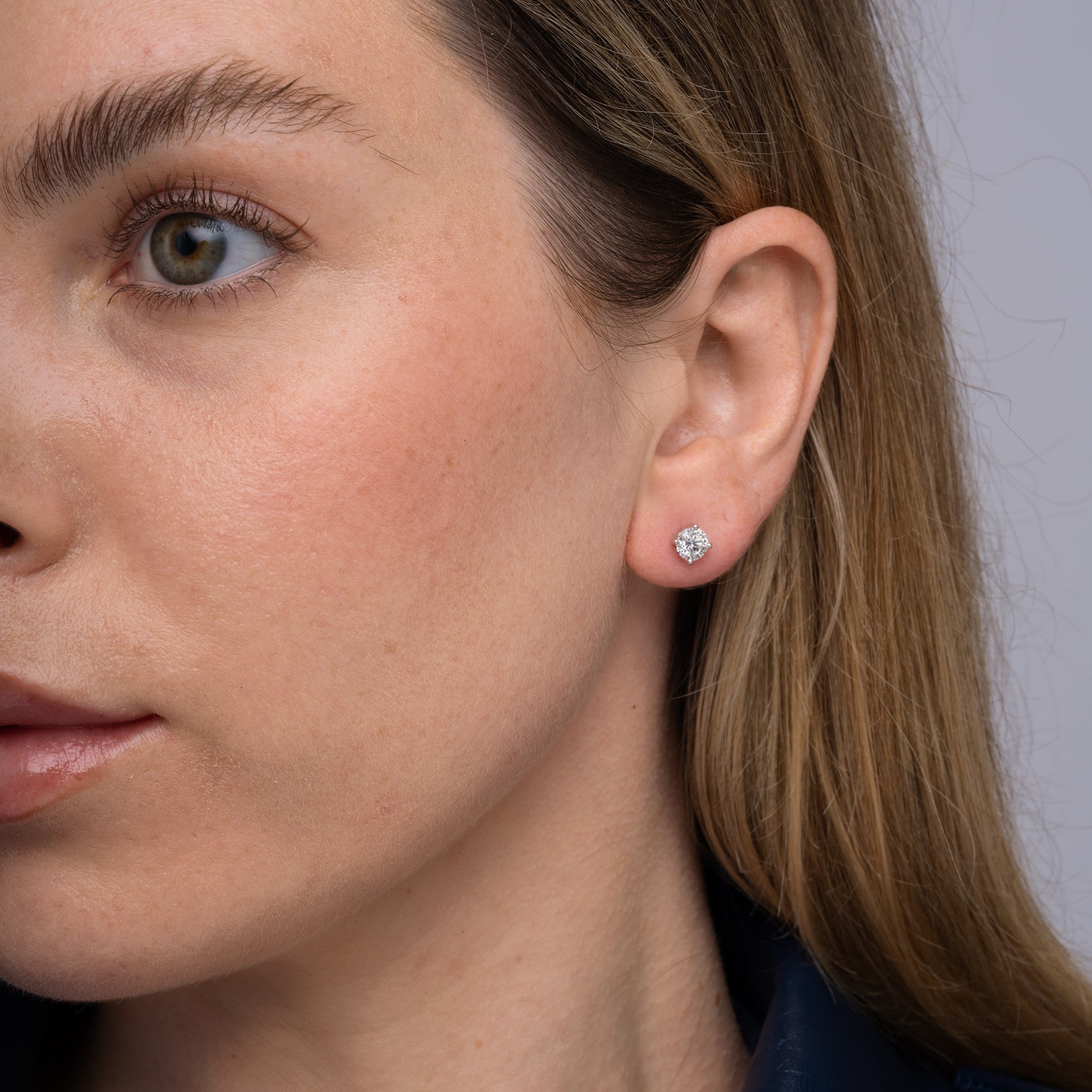 Round lab grown diamond stud earrings worn on the ear, 1.07 carat total weight