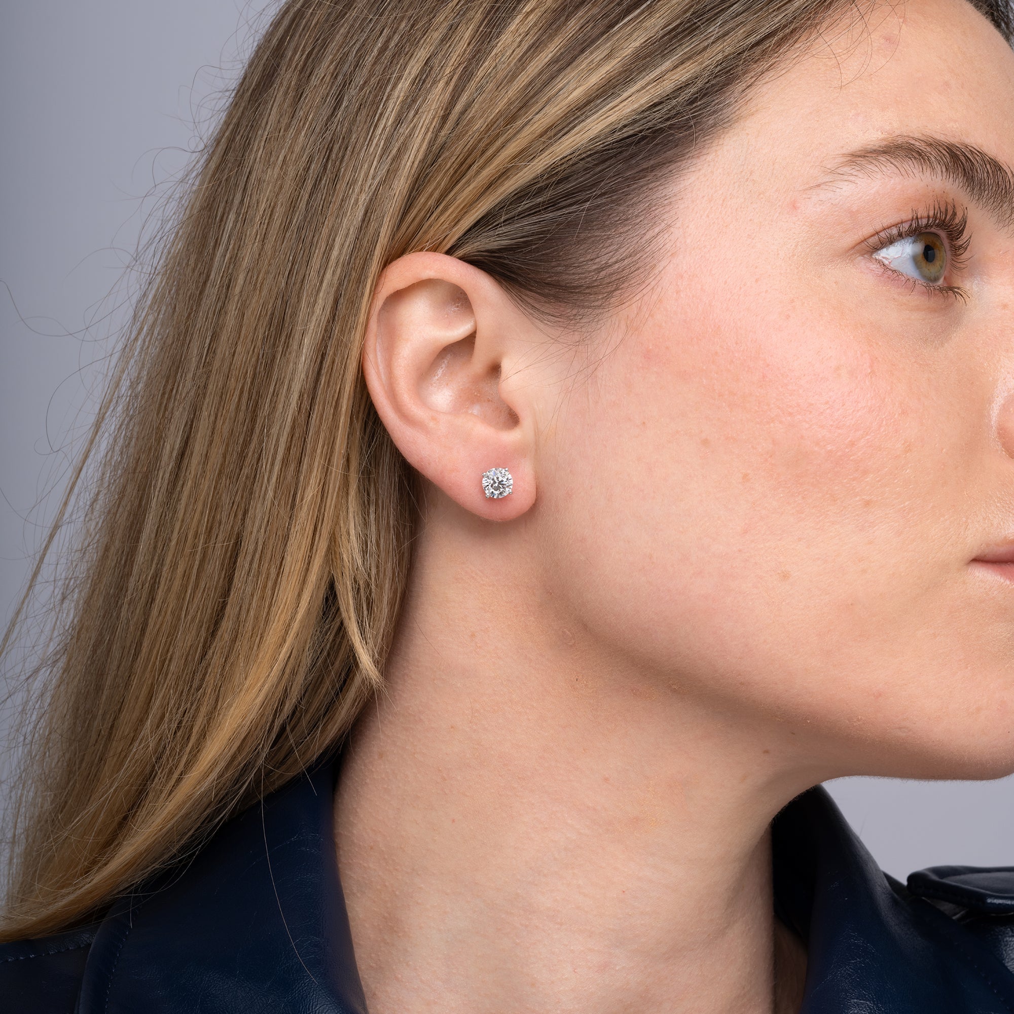 Round lab grown diamond stud earrings worn on the ear, 2.12 carat total weight