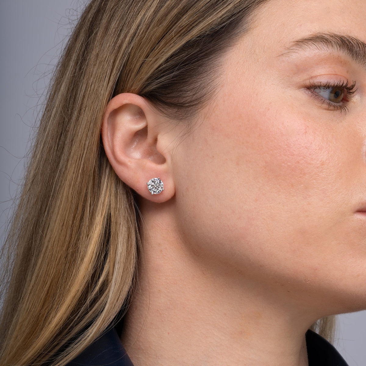Round lab grown diamond stud earrings worn on the ear, 4.14 carat total weight